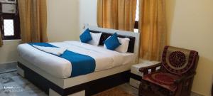 a bedroom with a bed with blue pillows and a chair at Rani Villa Family HomeStay in Varanasi