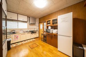 高千穂町にあるTakachiho Himuka no Yadoのウッドフロアの広いキッチン(白い冷蔵庫付)