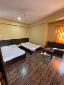 Habitación con 2 camas y un banco. en Hotel Vajra Inn & Apartments, en Pokhara