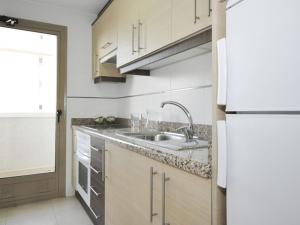 cocina con fregadero y nevera blanca en Apartamentos Larimar Unitursa, en Calpe