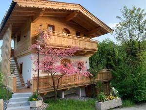 a wooden house with a tree with pink flowers at s'Zuhaus in Kirchbichl