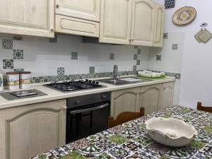 a kitchen with a stove and a sink and a table at Agriturismo Etna-Mare in Piedimonte Etneo