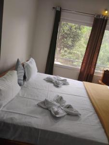 Una cama blanca con dos zapatos y una ventana. en Katakeri Deluxe Holiday Homes, en Madikeri