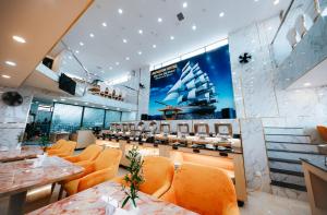 un restaurant avec des chaises orange et un bateau sur le mur dans l'établissement Napoleon Nha Trang Hotel, à Nha Trang