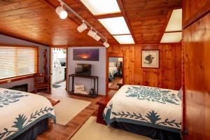 two beds in a room with wooden walls at Aloha Junction Guest House - 5 min from Hawaii Volcanoes National Park in Volcano