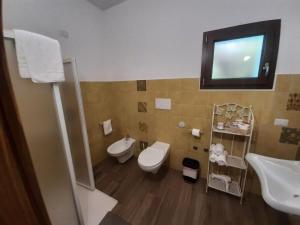 La salle de bains est pourvue de toilettes, d'un lavabo et d'un miroir. dans l'établissement Borgo Rurale Cares, à Dorgali