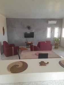 sala de estar con sillas rojas y TV de pantalla plana en La doré du Sénégal, en Somone