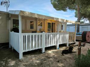 a house with a porch and a dog sitting in front of it at Mobil-home au Camping familial 4 étoiles Les Sables d'Or in Cap d'Agde