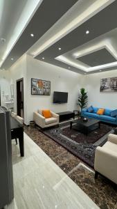 een woonkamer met blauwe banken en een televisie bij مارينا نجد للشقق الفندقية in Hotat bani tamim