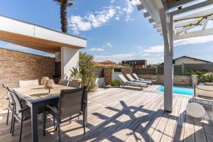 een patio met een tafel en stoelen en een zwembad bij Maison Bleue in Capbreton