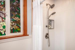 a shower in a bathroom with a window and a shower curtain at Aloha Junction Guest House - 5 min from Hawaii Volcanoes National Park in Volcano