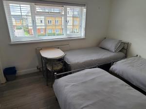 a room with three beds and a table and a window at GATWICK ROOMs in Ifield