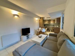 ein Wohnzimmer mit einem Sofa und einem TV in der Unterkunft Appartement bord de mer avec piscine in Vallauris