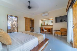 a bedroom with a bed and a desk and a television at Tanis Village - Luxury Villas in Gili Air