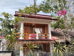 een huis met een balkon met roze bloemen bij Sambag Hideaway Bungalows in Moalboal