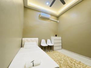1 dormitorio con 1 cama con 2 sillas blancas en Alyn Home Melaka Netflix, en Kampong Kerubong