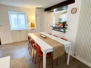 a dining room with a white table and red chairs at La chaumière de Walt : Petite maison proche Disney in Bussy-Saint-Georges +17 photos
