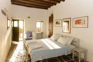 a white bedroom with a bed and a chair at Alisideri Studios in Karavostasi