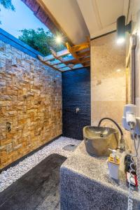 a bathroom with a stone wall and a sink at Tanis Village - Luxury Villas in Gili Air