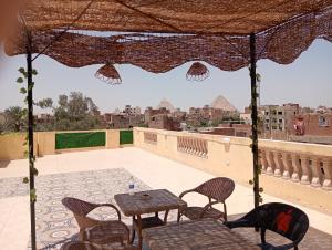 een patio met tafels en stoelen en uitzicht op de stad bij four pyramids Guest house in Caïro