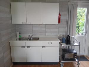 una cocina con armarios blancos y fregadero en Bed & Breakfast in ons Bakhuis, en Apeldoorn