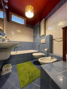 Baño de azulejos azules con 2 aseos y lavamanos en Rainbow House, en Intra