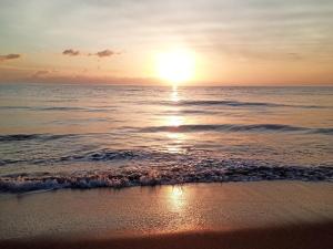 um pôr-do-sol numa praia com o oceano em U paradisu, T2 au calme avec accès privé mer em Biguglia