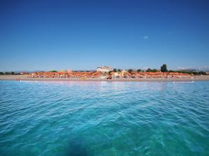 einen Strand mit einer Gruppe von Sonnenschirmen und dem Meer in der Unterkunft Grand Hotel President in Siderno Marina