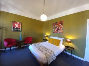 sypialnia z łóżkiem i 2 czerwonymi krzesłami w obiekcie Hostellerie du Chateau Bellenaves w mieście Bellenaves