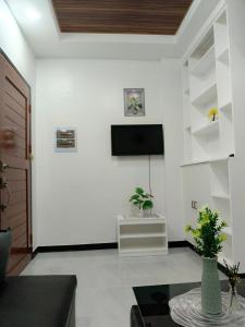 Elle comprend un salon doté d'une télévision et d'un mur blanc. dans l'établissement Kings' Palms Residence04, à General Santos