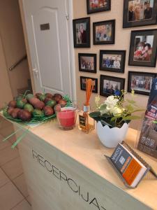 a counter with a bowl of fruit and pictures on the wall at Bed and Breakfast Majesty in Niš