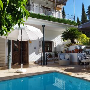 a house with an umbrella and a swimming pool at Suite Comares in Granada