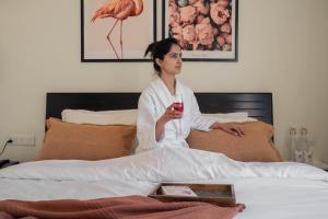 a woman sitting in bed holding a glass of wine at PerfectStayz B2L Hills Tapovan in Rishīkesh