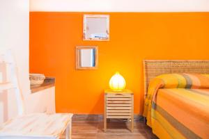 BoscotrecaseにあるVilla Giulia - Vesuvio Guest House Pompei Sorrentoのオレンジ色の部屋(ベッド1台、ナイトスタンドのランプ付)