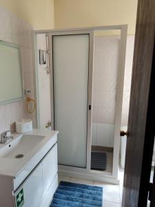 a bathroom with a sink and a glass shower door at casa na Torre in Machico +23 photos
