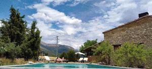 a pool with people sitting at a table next to a building at Masia Serret in Àger