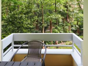 einen Stuhl auf einem Balkon mit Bäumen im Hintergrund in der Unterkunft Stupendo monolocale in Minusio