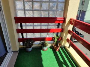 a red bench in a room with potted plants at casa na Torre in Machico