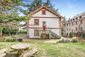 a large white house with a table and benches at Acogedor chalet en la Sierra in Cercedilla