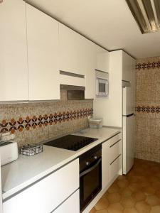 uma cozinha com armários brancos e um forno com placa de fogão em Acogedor chalet en la Sierra em Cercedilla