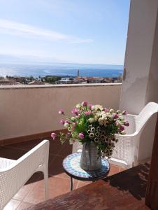 a vase with flowers sitting on a table on a balcony at Scario house in Scario