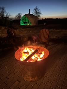 a fire pit with two chairs and a green tent at Glempings lāčuks 