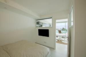 een witte slaapkamer met een bed en een televisie bij Sea Side Dream-Amazing sea view best location in town in Eilat