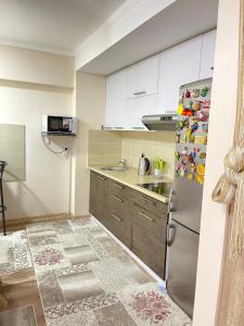 a kitchen with white cabinets and a stainless steel refrigerator at 2 комнатная квартира студио на Иссык куле in Chok-Tal