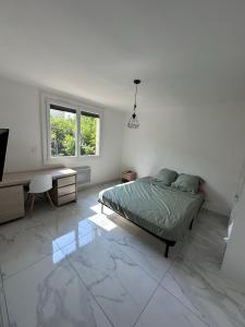 a bedroom with a bed and a desk and a window at Appartement climatisé dans maison in Alès