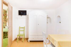 BoscotrecaseにあるVilla Giulia - Vesuvio Guest House Pompei Sorrentoの白いキャビネット、テーブル、椅子が備わる客室です。