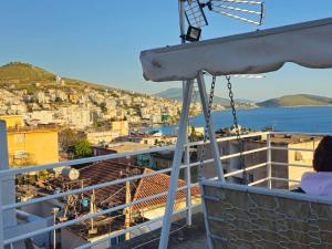 une personne assise sur un balcon donnant sur une ville dans l'établissement Joen Guesthouse, à Saranda