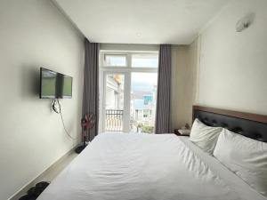 a bedroom with a bed with a television and a window at Phuong Vy 2 in Da Lat