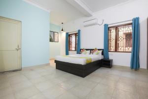 a bedroom with a bed in a room with blue curtains at Super OYO JANAPATH INN in Khandagiri