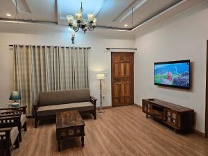 a living room with a couch and a tv at Laspa Cottage, Bhimtal in Bhīm Tāl